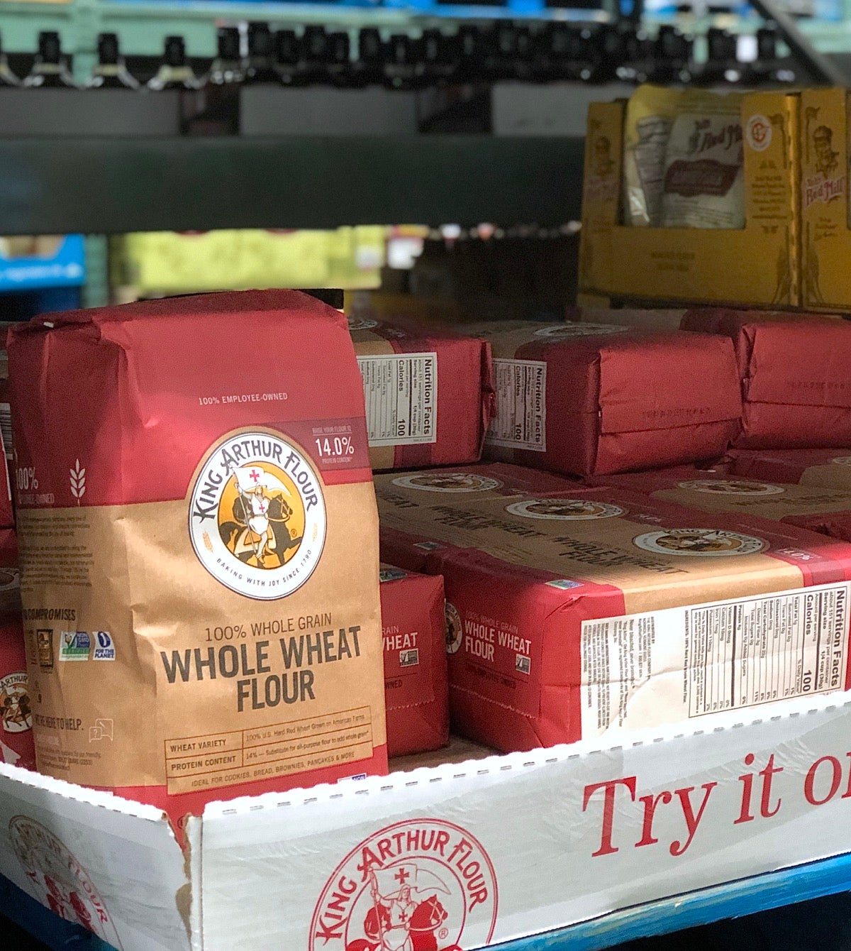 Bag of King Arthur Premium Whole Wheat Flour on the shelf of a warehouse store.