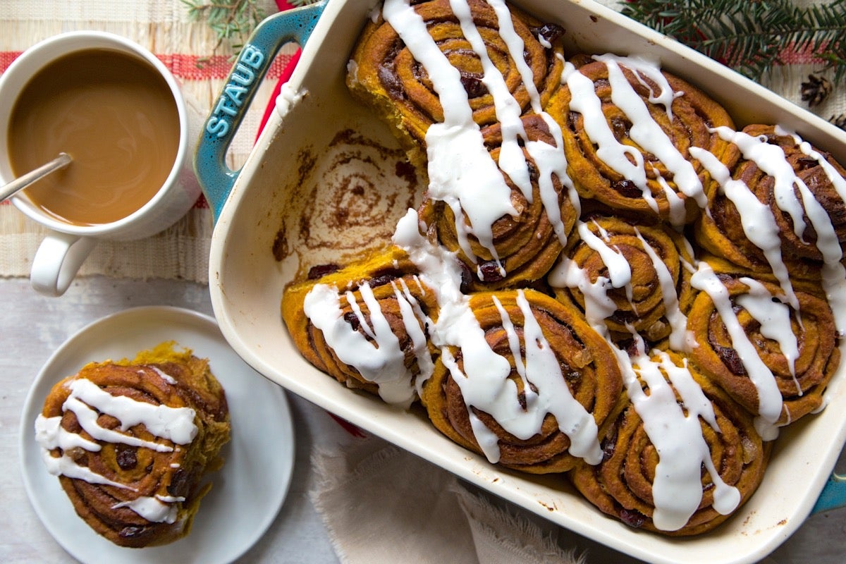 Cinnamon swirl pumpkin rolls iced with confectioners' sugar icing, ready to serve