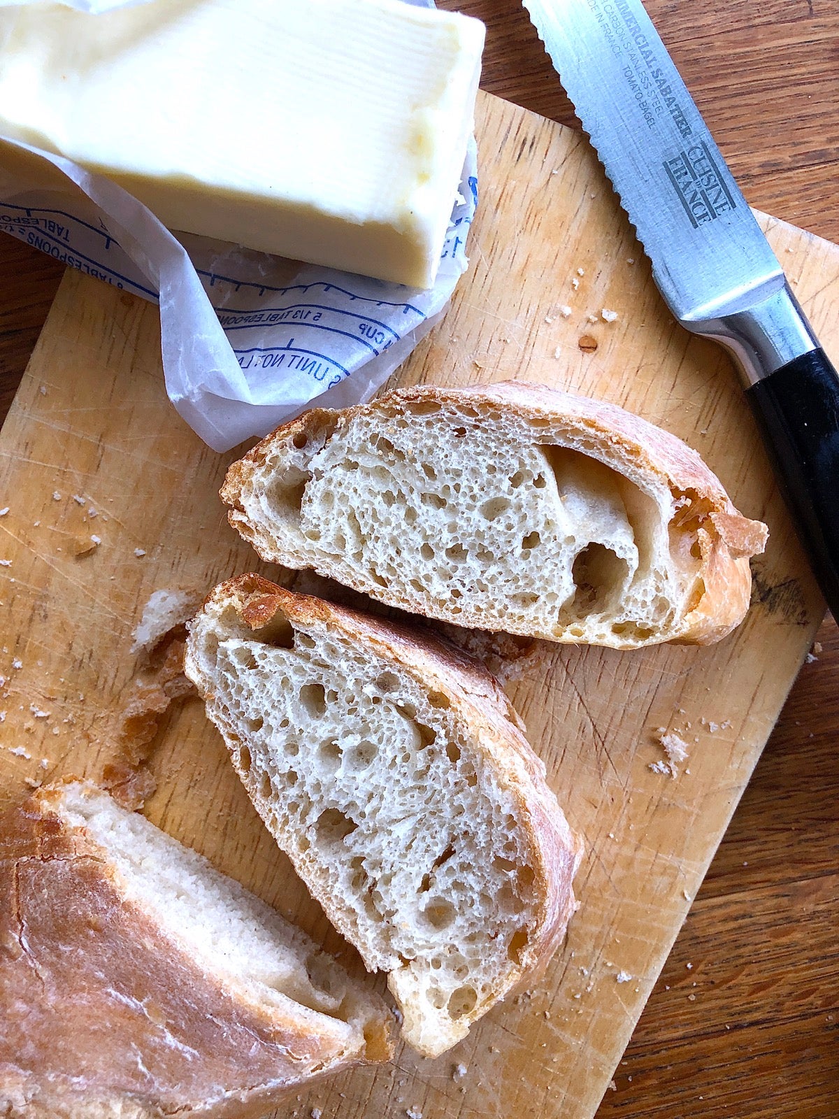 Sliced baguette on a cutting board with a stick of butter.