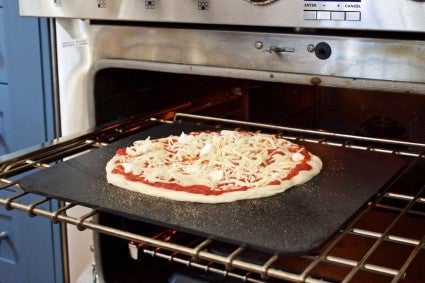 Unbaked pizza on baking steel going into the oven