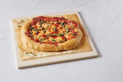 Baked pizza on a parchment-lined baking stone