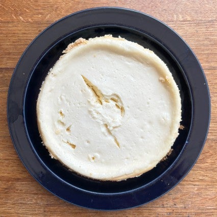 Whole 6" cheesecake on a plate, center showing a deep crack.