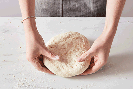 A baker kneading dough by hand on the counter. 