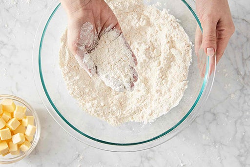 A baker holding a handful of flour to show the sandy texture after the shortening has been cut in. 