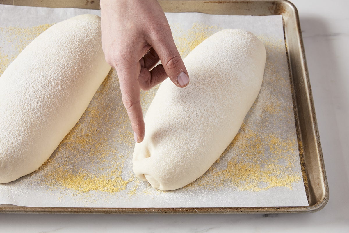 a baker carries a cart with a baking tray with raw dough into a