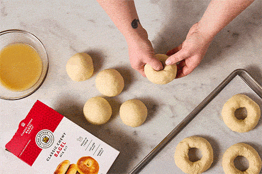 Animated gif showing a person creating a hole in the center of bagel dough and working the hole into a larger bagel shape.