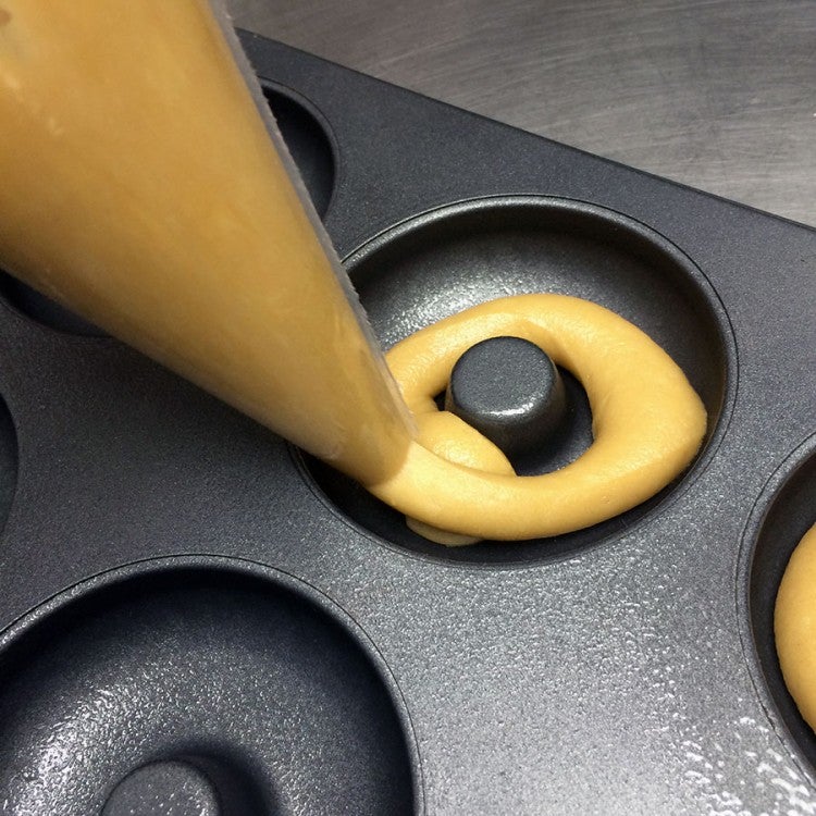 Piping batter into the wells of the pan. 