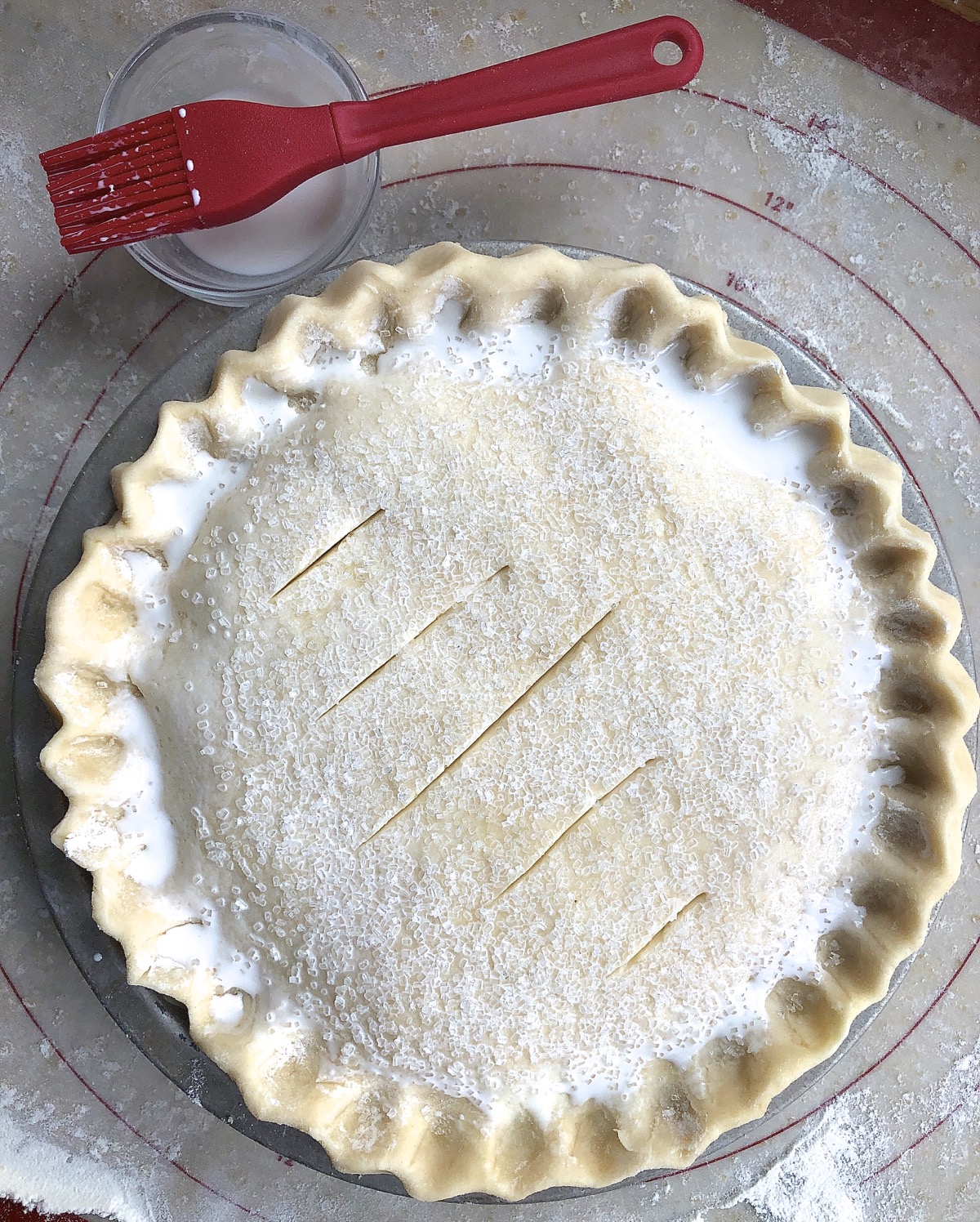 Unbaked peach-apricot-raspberry pie sprinkled with sugar and vented with slashes