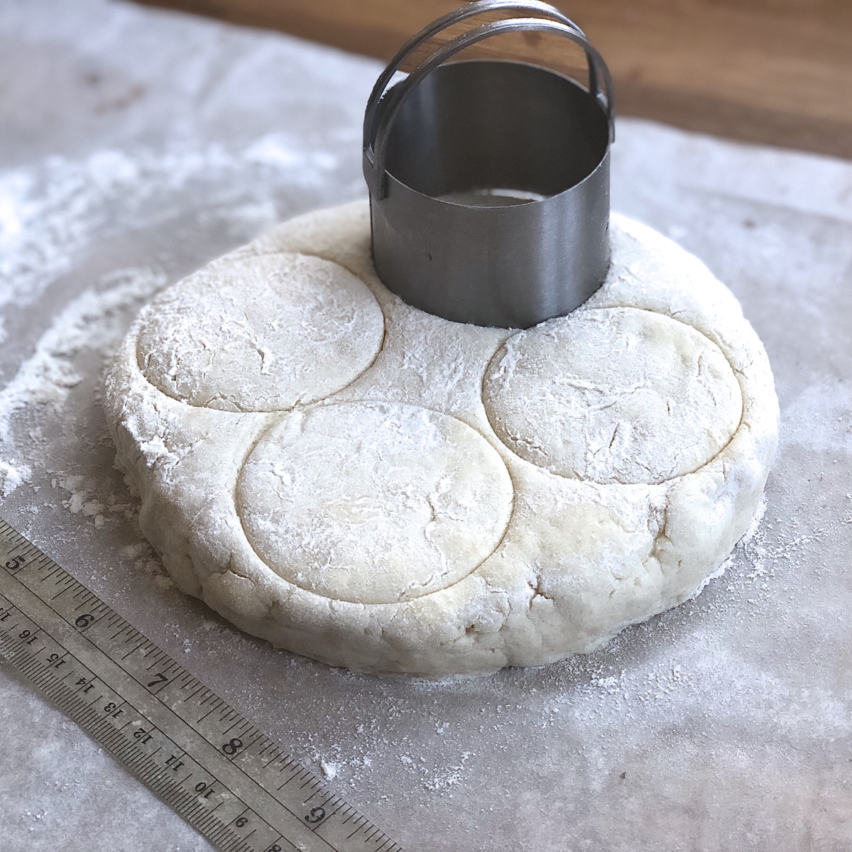 A 6" round of biscuit dough about to be cut with a biscuit cutter.