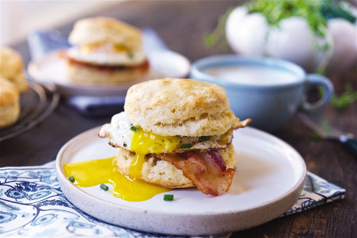 Sourdough breakfast sandwich with bacon and egg served on a plate.