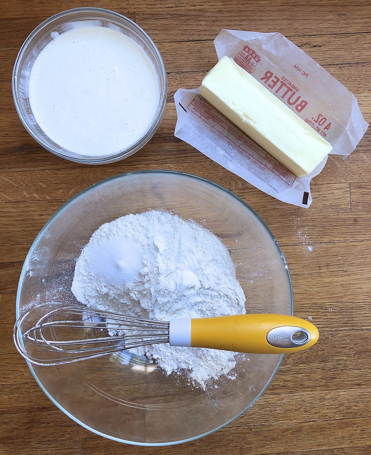All the components for sourdough biscuits: dry ingredients in a bowl, butter, and starter.