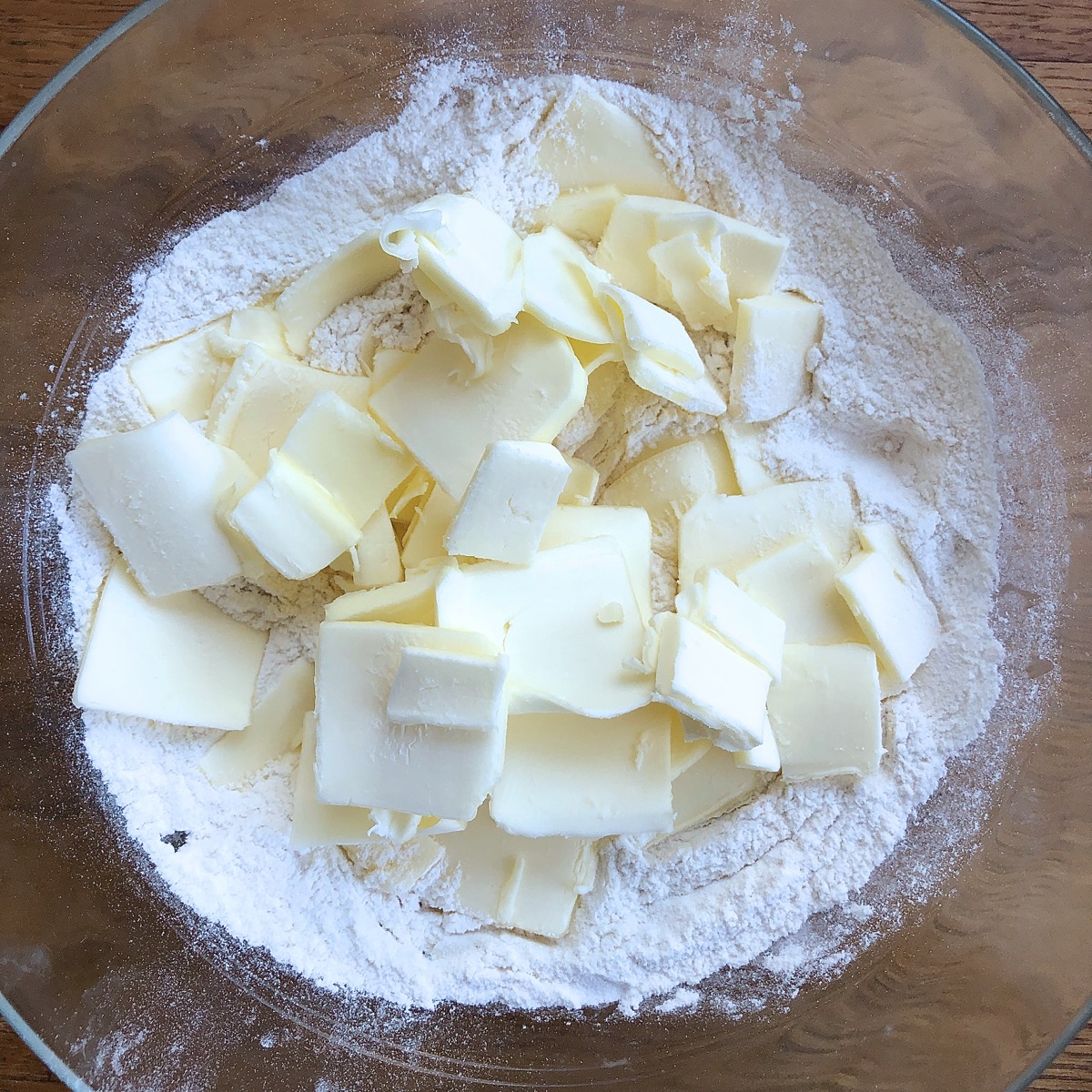 Sliced butter and dry ingredients in a bowl, ready to be combined.