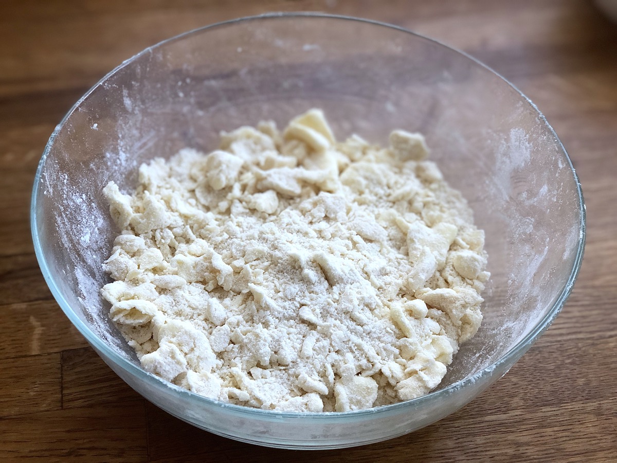 A crumbly mixture of flour, salt, baking powder, and butter in a bowl, ready for starter to be added.