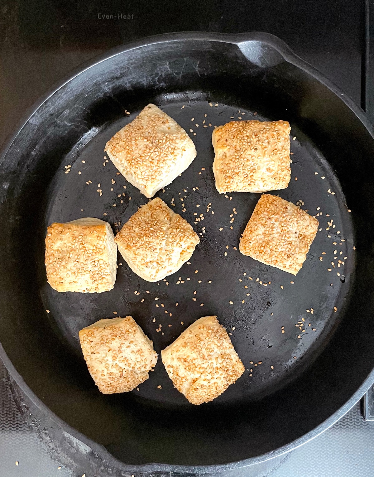 Square biscuits, topped with sesame seeds, baked in a round cast iron frying pan