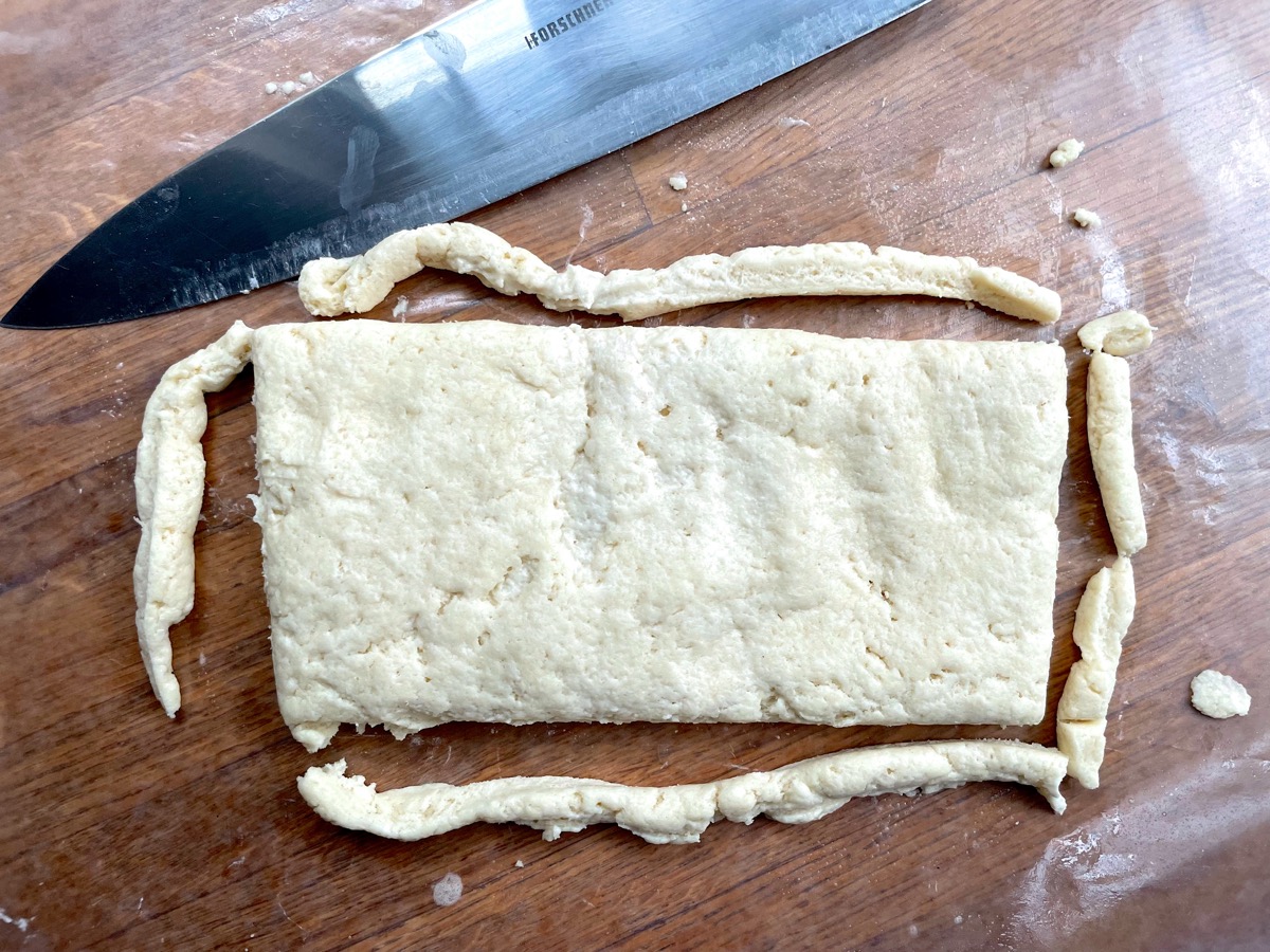 Biscuit dough patted into a rectangle, its edges trimmed straight.