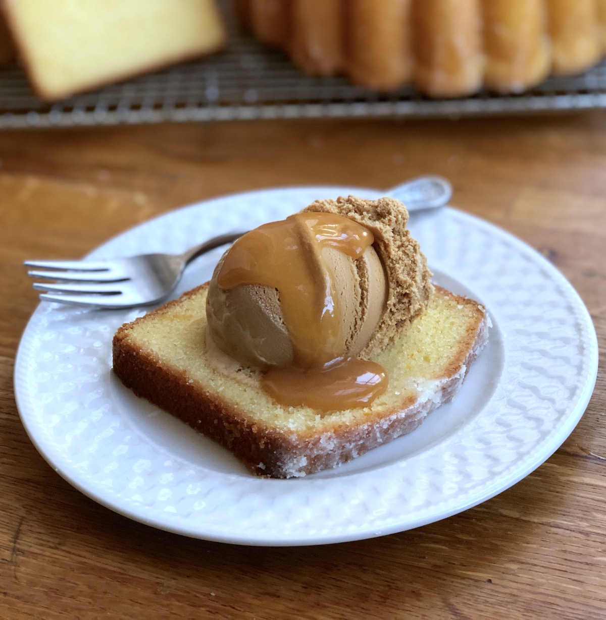 Slice of orange pound cake topped with caramel ice cream and drizzled with butterscotch sauce.