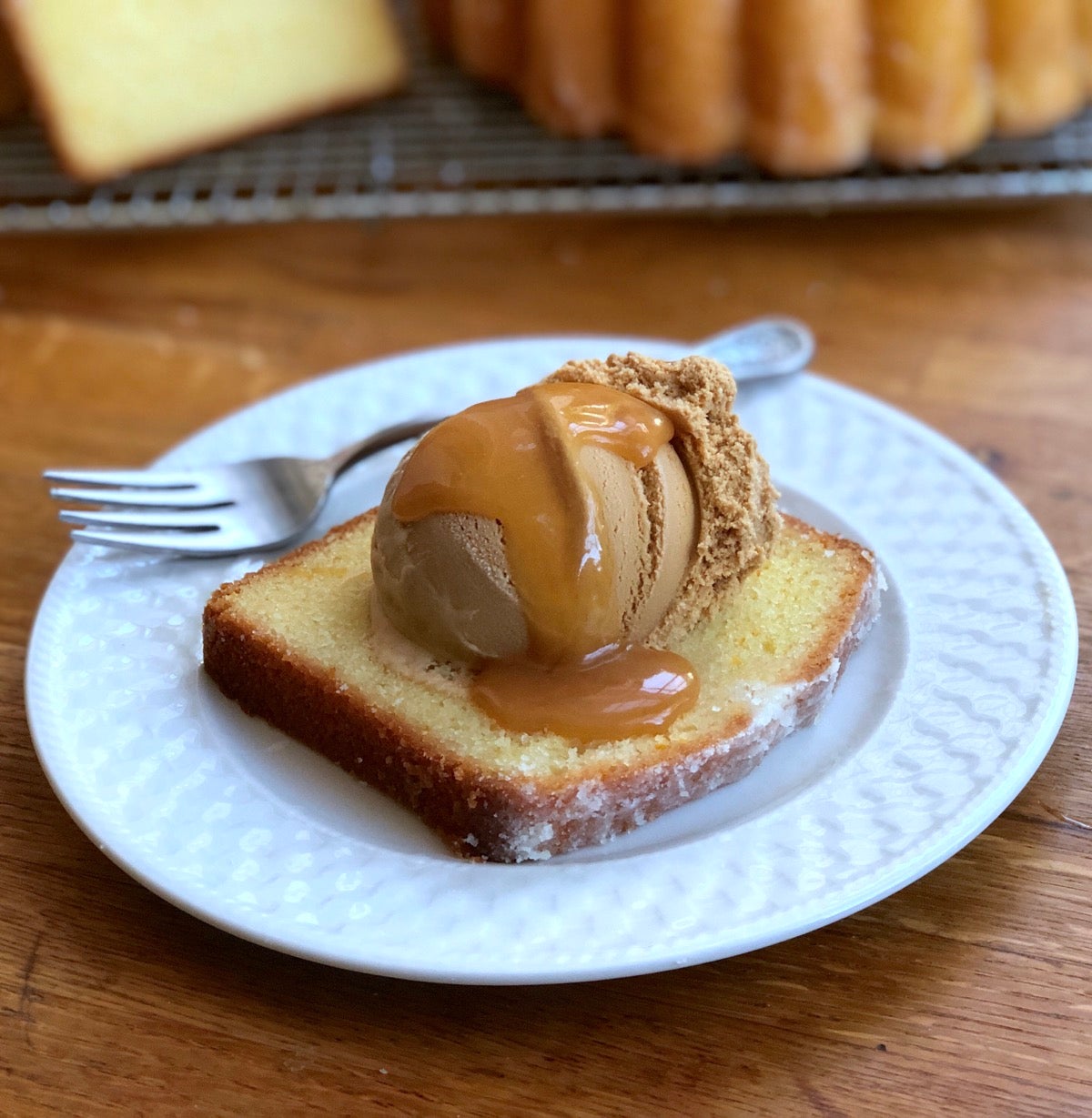 Slice of orange pound cake topped with caramel ice cream and drizzled with butterscotch sauce.