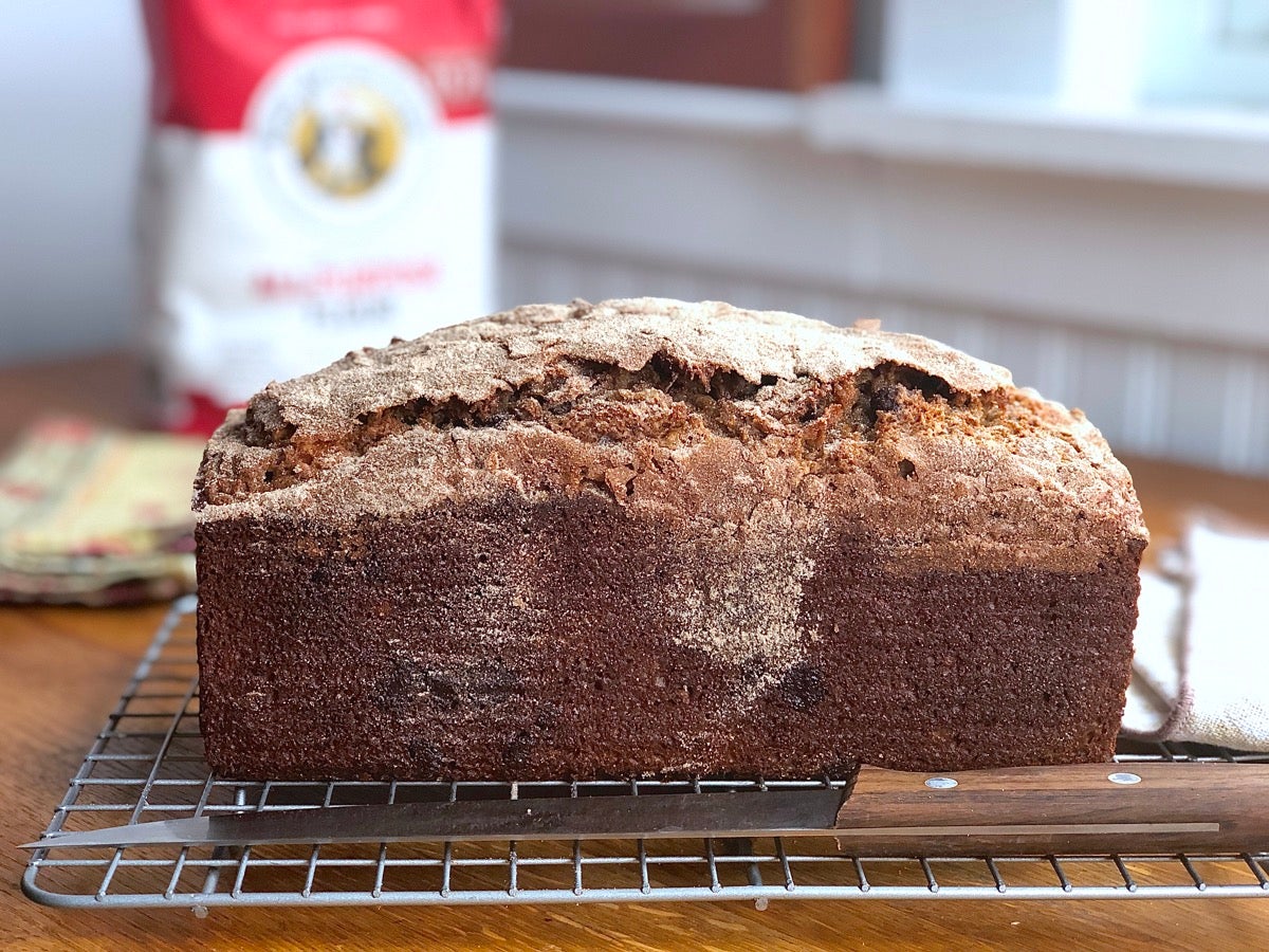 Loaf of whole grain banana bread on a cooling rack.