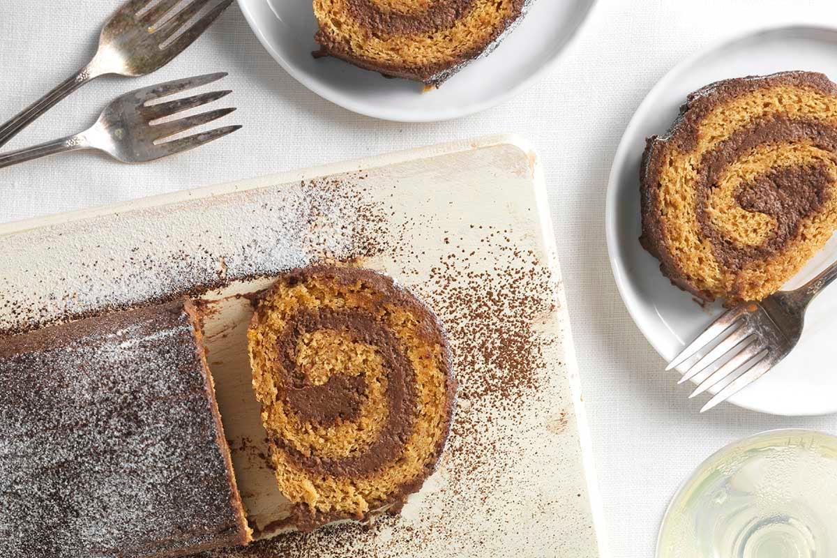 Sliced almond roll, with plated slices showing the cake swirls