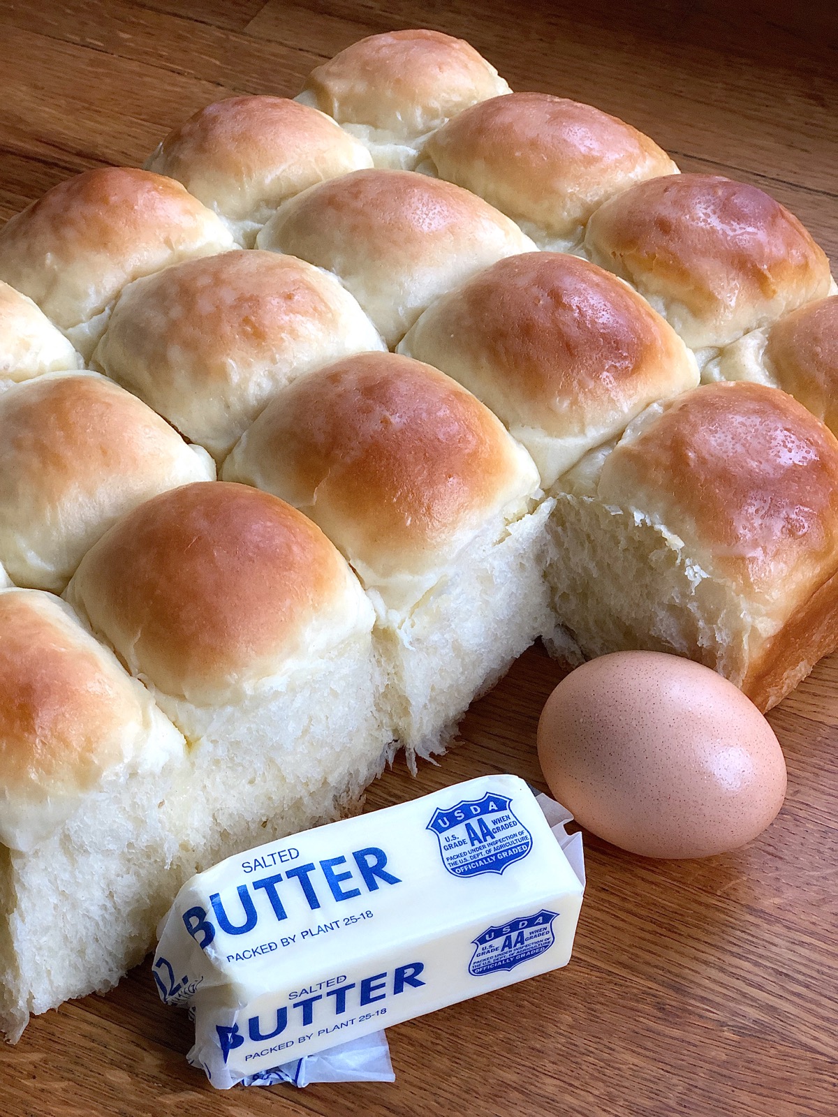 Amish Dinner Rolls shown beside a large egg and a stick of butter, for scale.