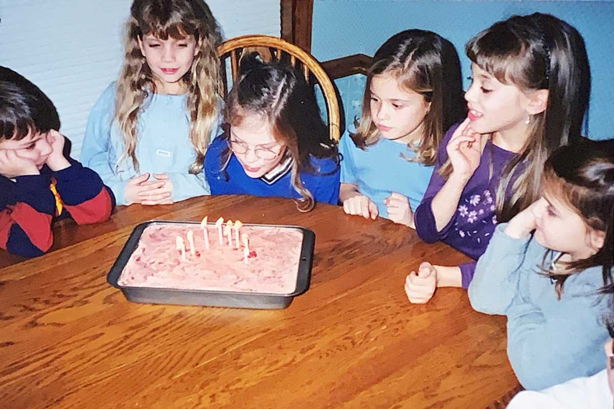 Blowing out candles on strawberry cake at childhood party