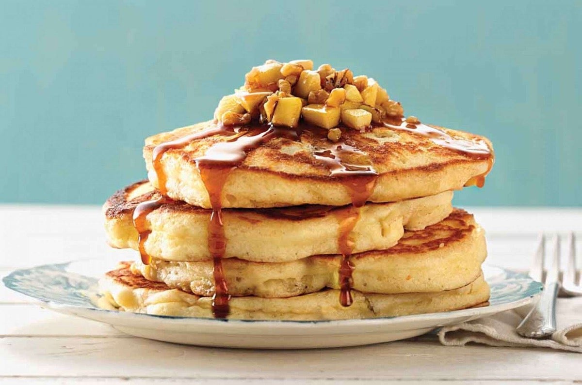 Plate of pancakes drizzled with boiled cider syrup, garnished with diced sautéed apples.