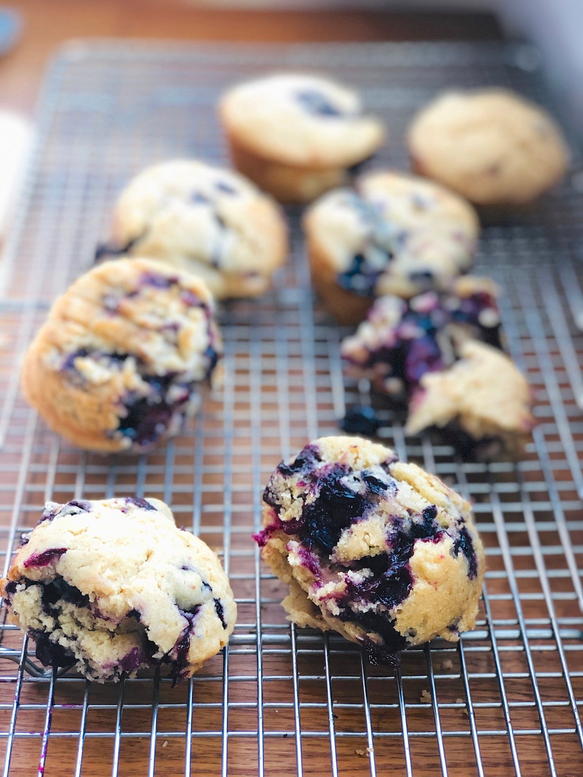 Blueberry muffins on a cooling rack, some smashed and falling apart.