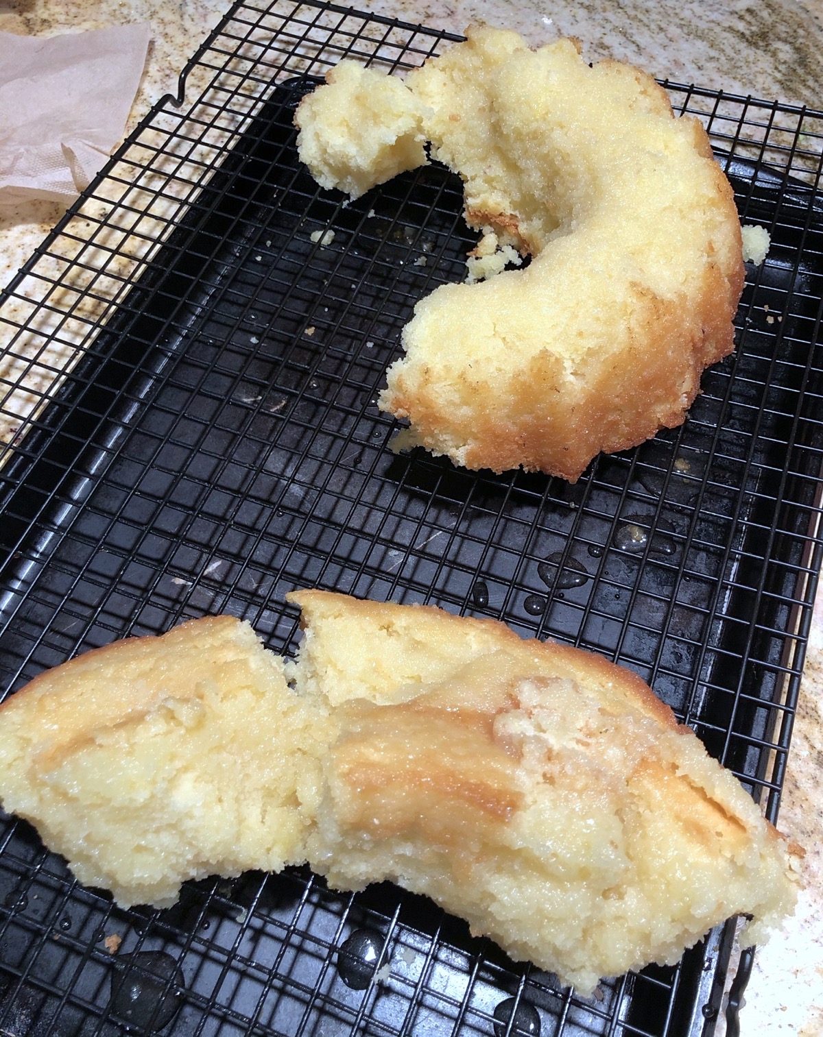 Vanilla Bundt cake in two ragged halves on a cooling rack.
