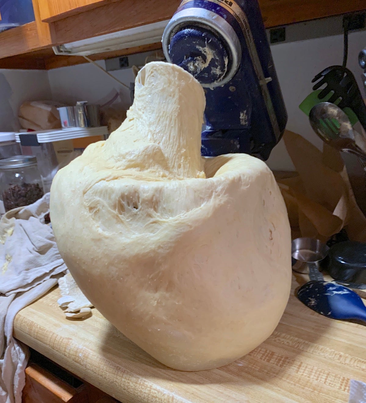 KitchenAid mixer with yeast dough overflowing the bowl and running across the table. 