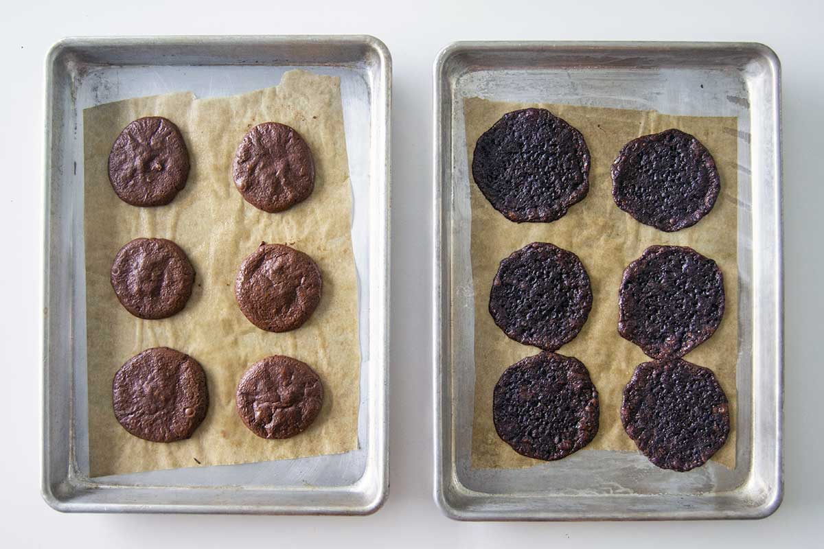 Pan of egg white chocolate crinkle cookies next to pan of messy, sticky, poorly baked aquafaba chocolate crinkle cookies