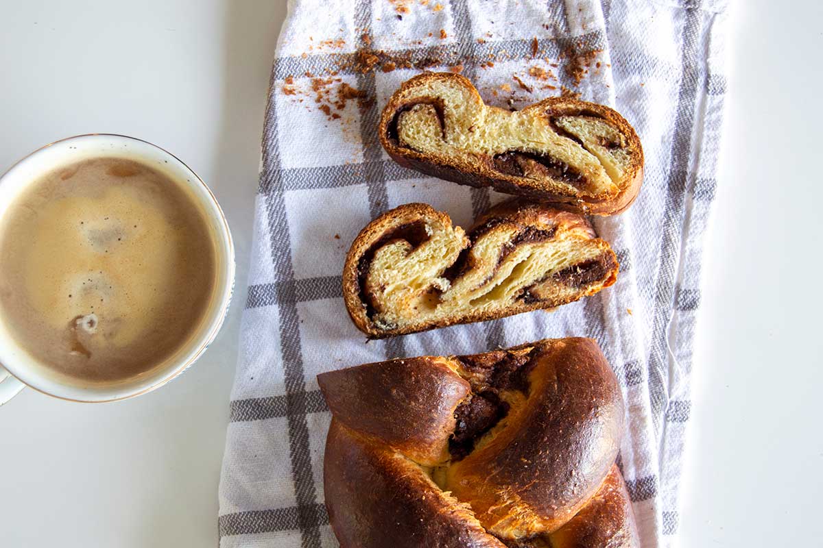 Sliced babkallah next to cup of coffee