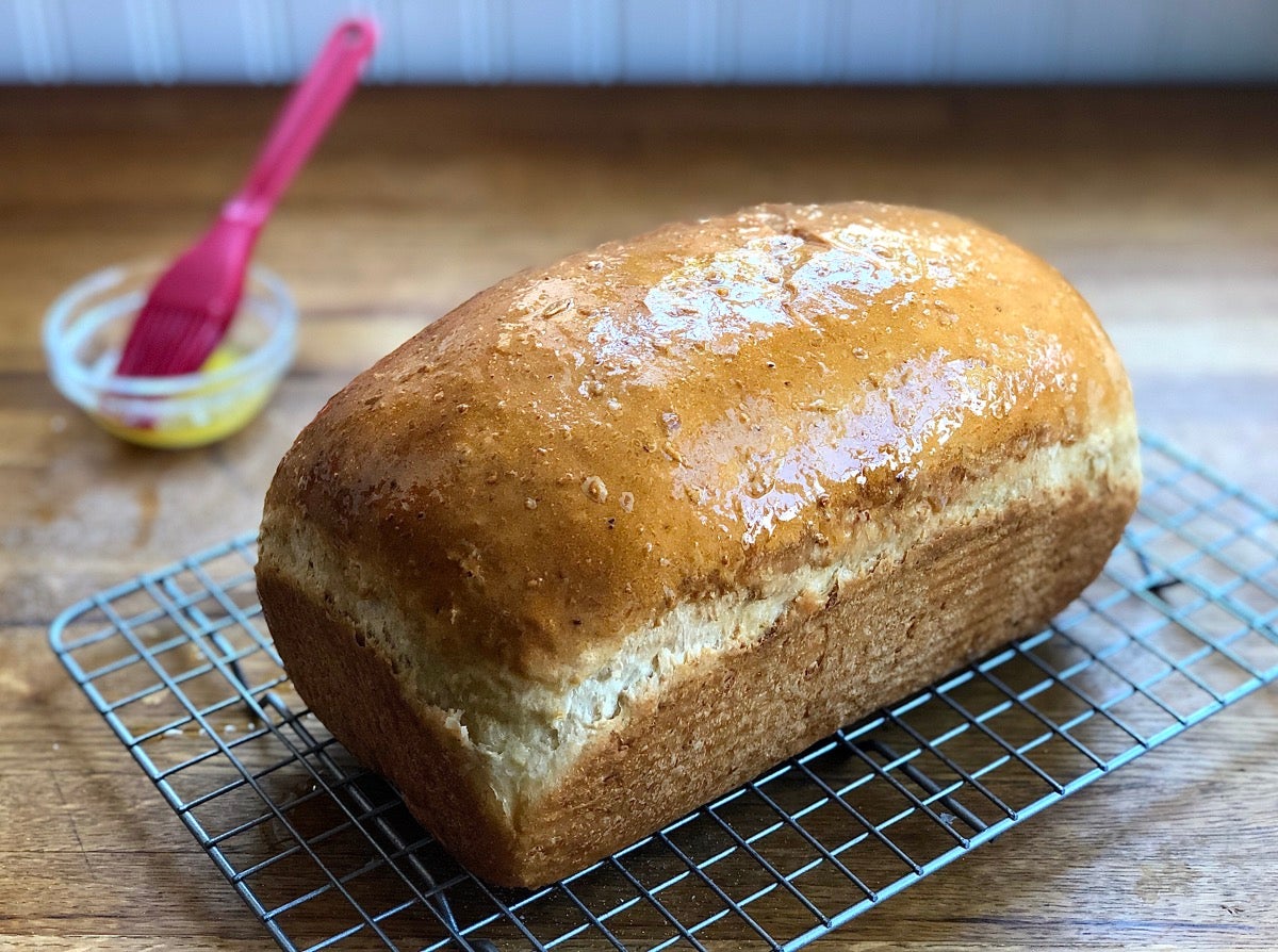 Oatmeal bread hot out of the oven, brushed with butter and set on a cooling rack