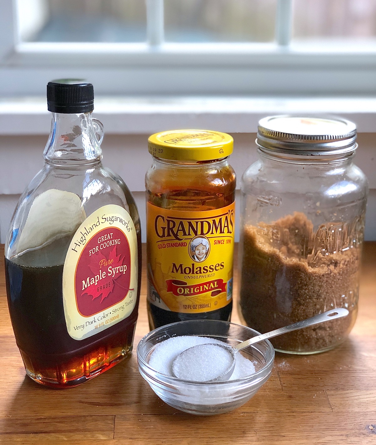 Glass containers of maple syrup, molasses, brown sugar, and white granulated sugar