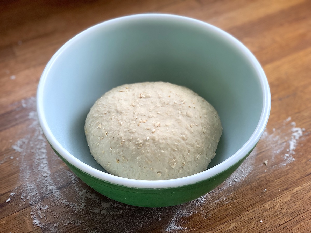 Oatmeal bread dough in a bowl, ready to rise