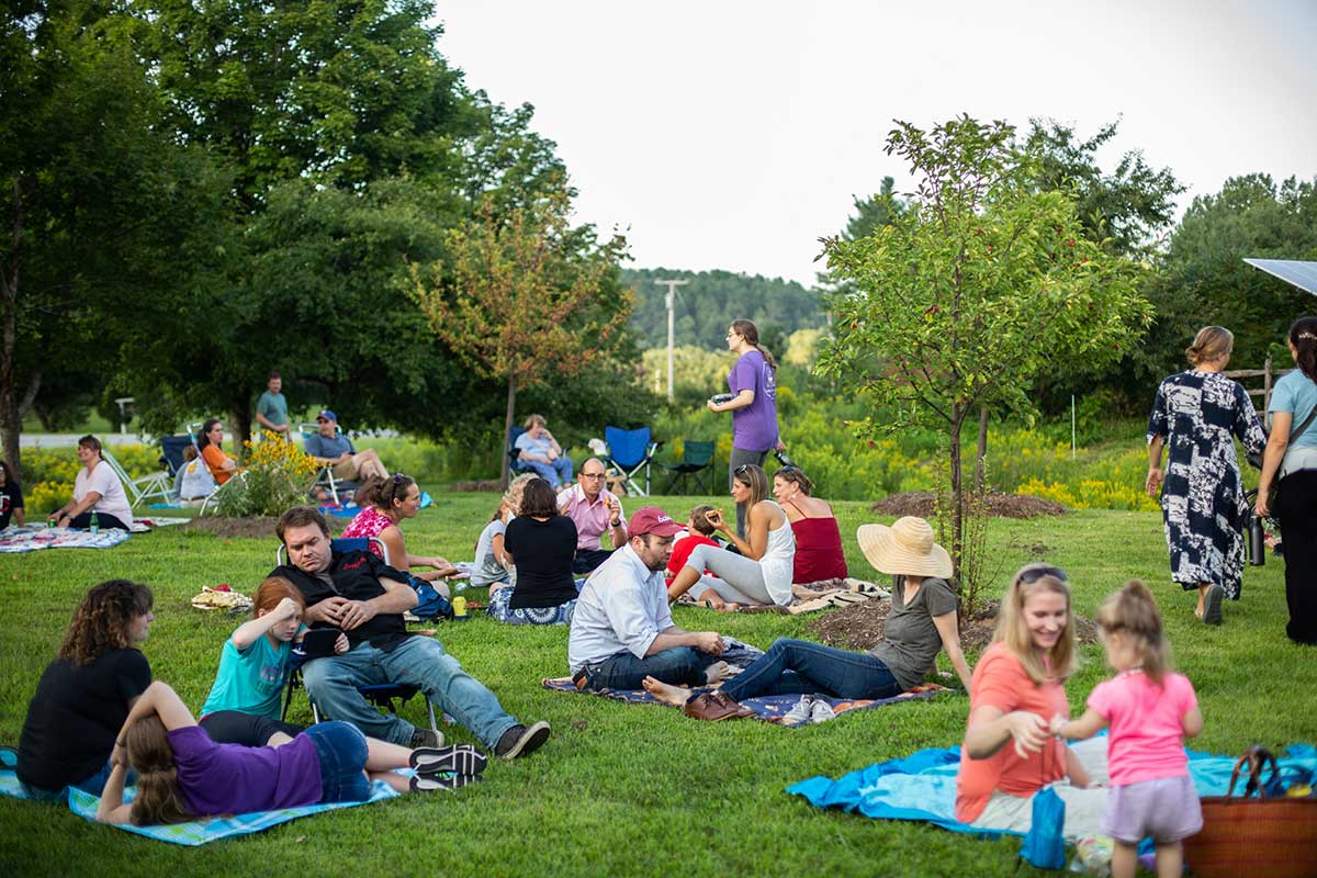 Families sitting on the grass enjoying a picnic dinner