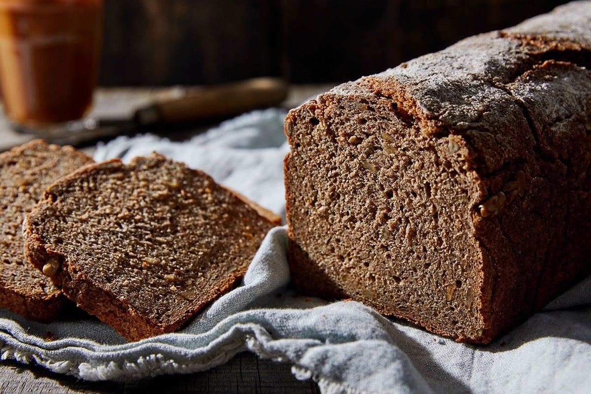 Loaf of Vollkornbrot, a dense, heavy rye bread, sliced on a cloth.