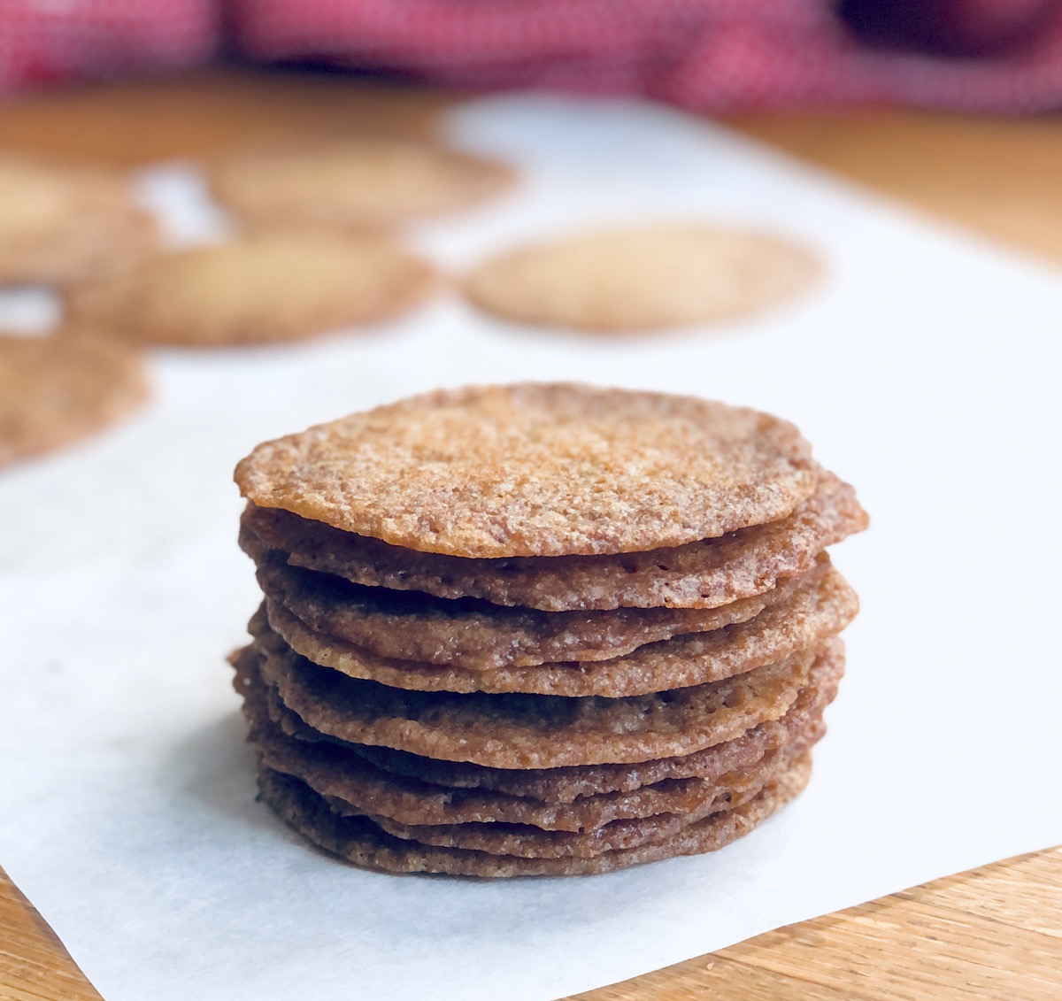 Stack of ultra-thin Buttersnap cookies on a baking sheet.