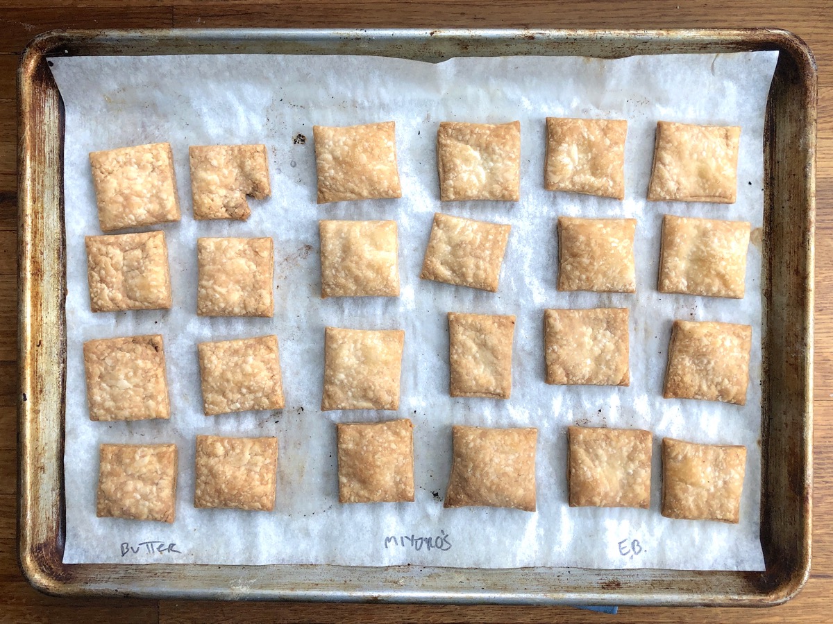 Squares of baked pie pastry, made with three different types of butter, on a baking sheet. 