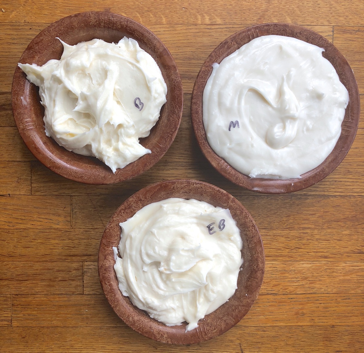 Buttercream frosting in three small bowls, each made with a different type of butter to show differences in color and texture.