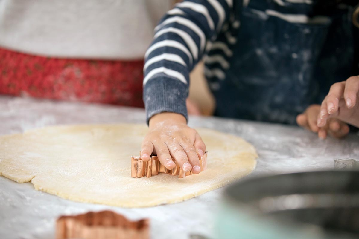 A child's hands using a cookie cutter to cut cookie dough
