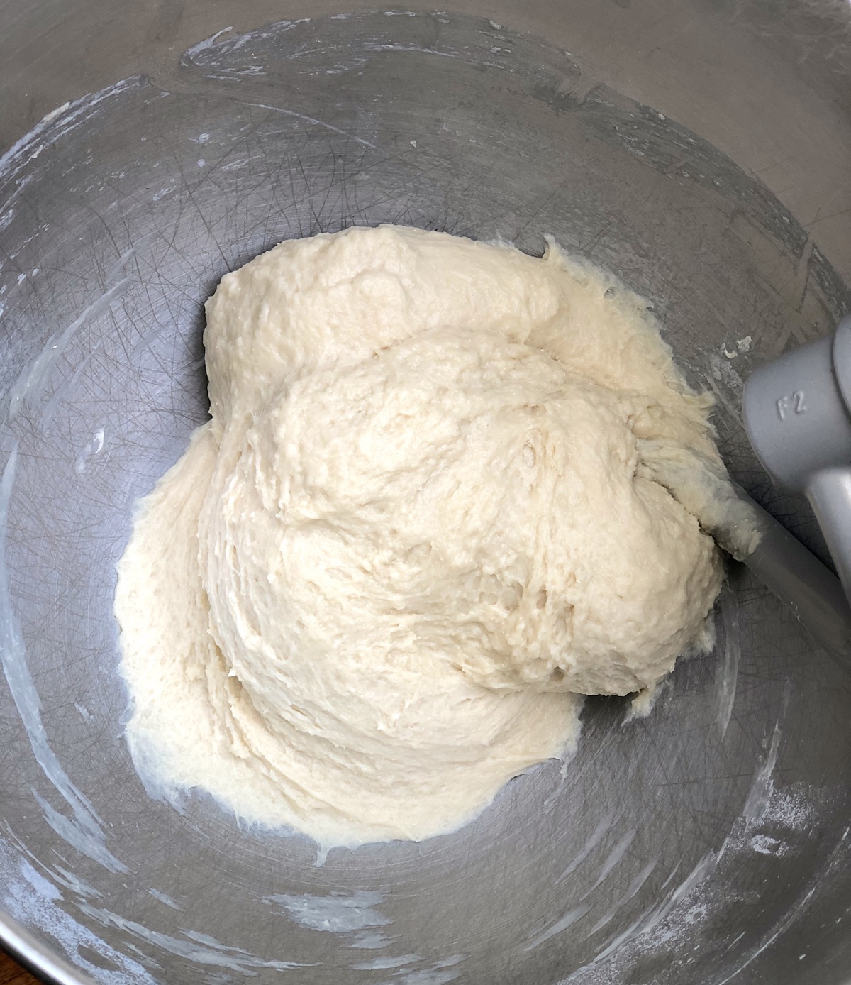 Sticky kneaded yeast dough in the bowl of a stand mixer.
