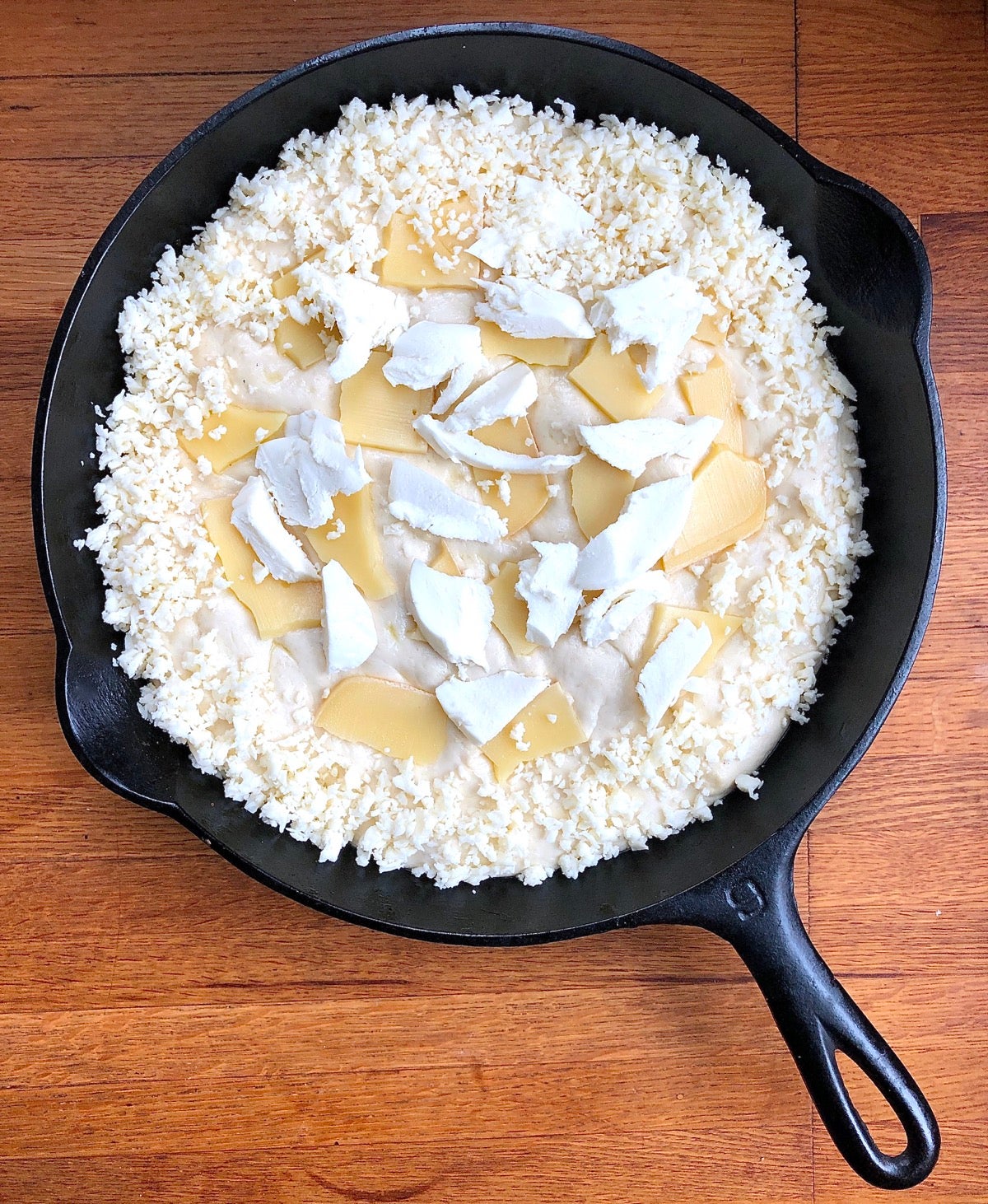 Pizza in a cast iron pan, topped and ready to bake.