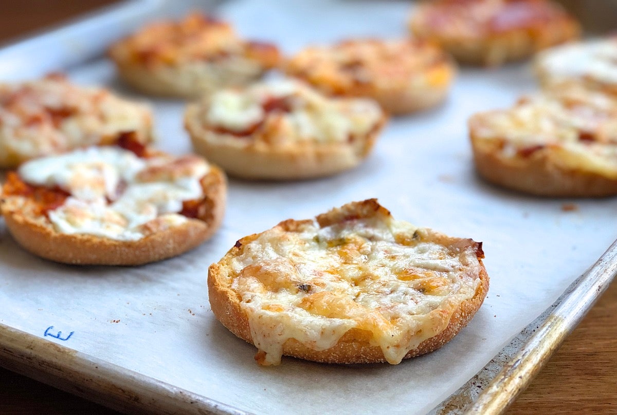 English muffin topped with sauce and cheddar cheese, baked.