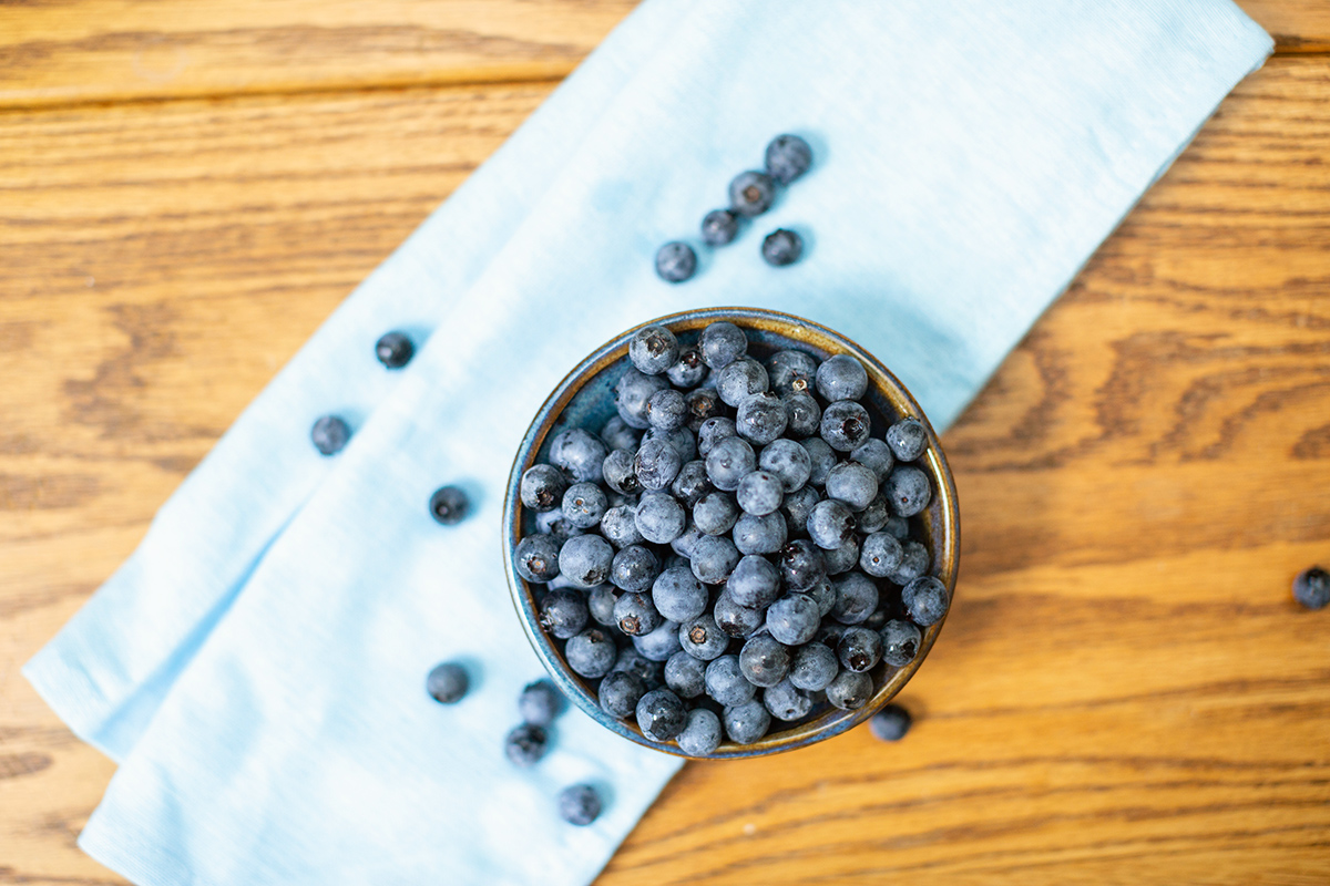Fresh blueberries in a bowl on a table with a blue linen, ready for baking