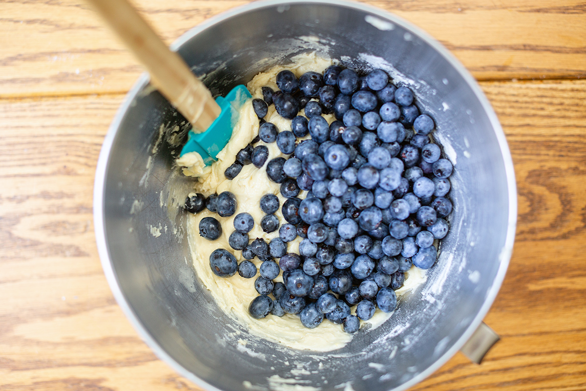 A mixing bowl of Blueberry Buckle Coffeecake batter with blueberries on top, ready to be folded in