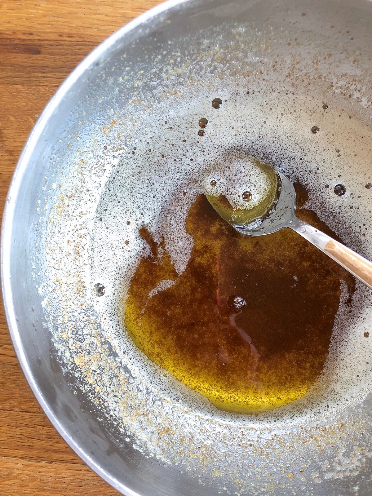 Brown butter in a skillet showing dark milk solids at the bottom of the pan.