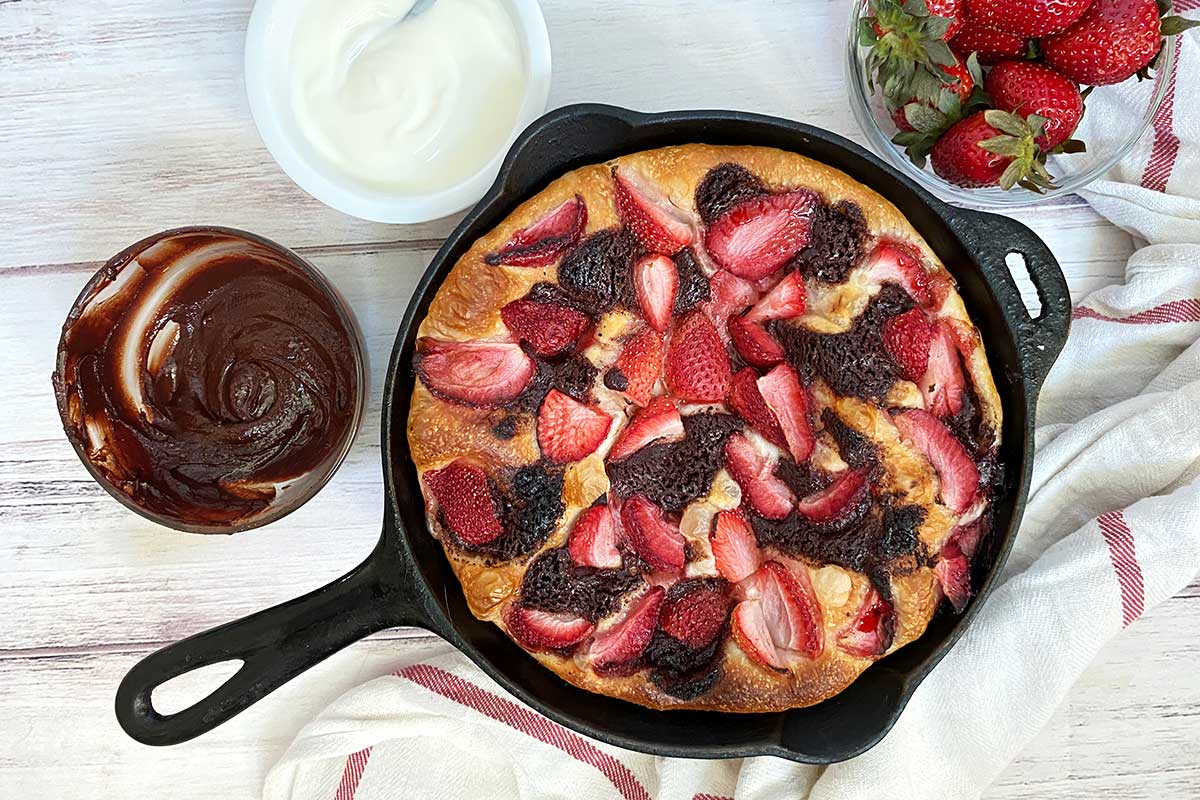 A sweet pizza topped with strawberries, chocolate ganache, and whipped cream