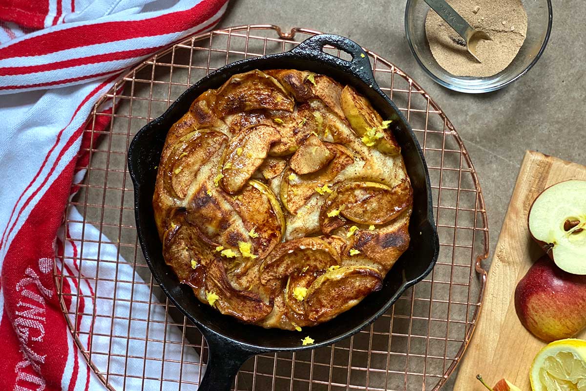 A sweet pizza topped with apples, cinnamon, and brown butter in a cast iron pan