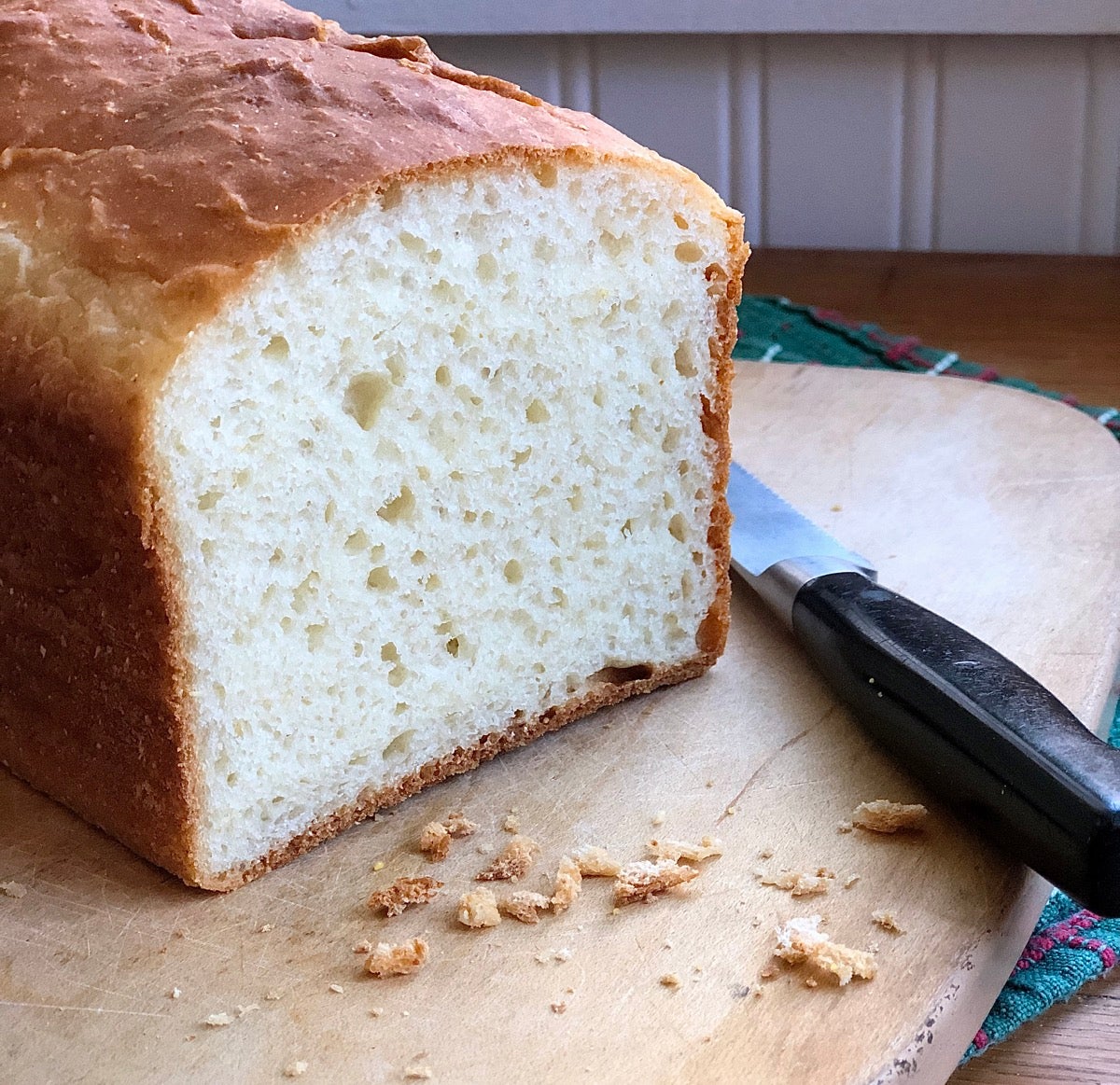 Loaf of bread on a cutting board with knife, end sliced off.