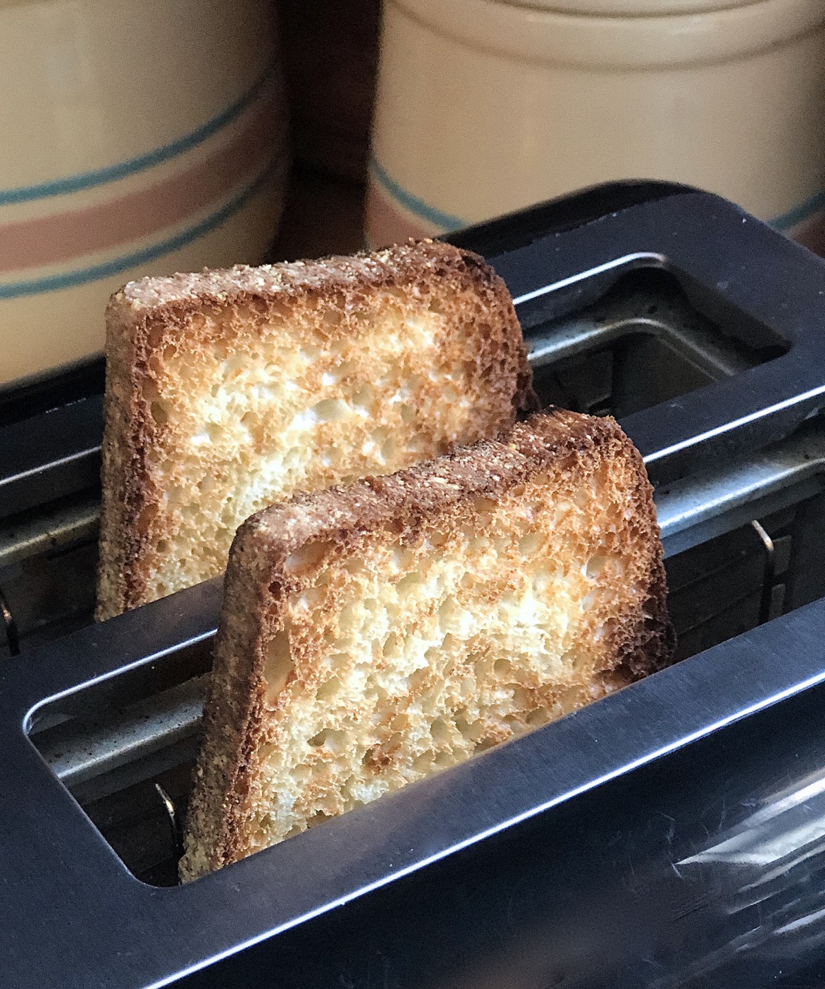 Two slices of toasted bread sitting in a toaster, freshly popped.
